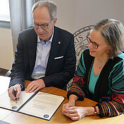 JMU-Präsident Paul Pauli und Vizepräsidentin Doris Fischer bei der Unterzeichnung im Senatssaal. 