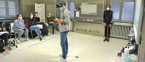 Virtual-Reality-Seminar an der Uni Würzburg. Die Studierenden verfolgen den Fall auf einer Leinwand rechts im Bild. 