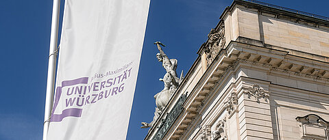Blick aufs Hauptgebäude der Uni Würzburg mit Uni-Fahne.
