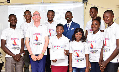 Mit BEBUC-T-Shirts und Bringmanns Ehrendiplom: Die BEBUC-Stipendiatinnen und -Stipendiaten von Mbujimayi, darunter der Sprecher von UOM, Felly Nzengu (dritter von links), die Sprecherin vom Institut Kristo Mfumu, Esther Ngoya (vierte von rechts) und der Tutor, Hervé Mbuyamba (im blauen Anzug, hintere Reihe). Mit BEBUC-T-Shirts und Bringmanns Ehrendiplom: Die BEBUC-Stipendiatinnen und -Stipendiaten von Mbujimayi, darunter der Sprecher von UOM, Felly Nzengu (dritter von links), die Sprecherin vom Institut Kristo Mfumu, Esther Ngoya (vierte von rechts) und der Tutor, Hervé Mbuyamba (im blauen Anzug, hintere Reihe).